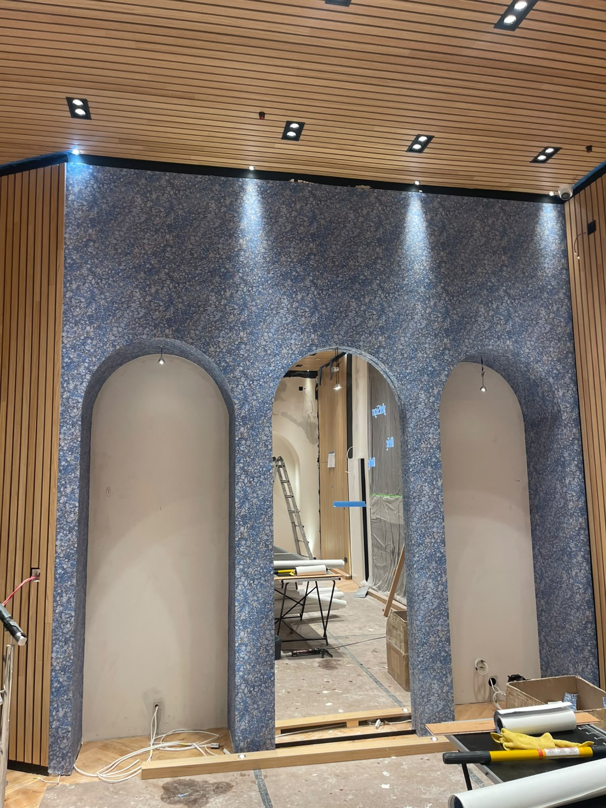 Blue terrazzo-print wallpaper wrapping arched openings in a bespoke joinery build