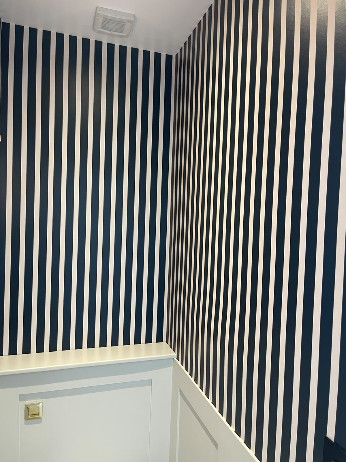 Navy and white striped corridor with fresh white wainscoting and brass detailing