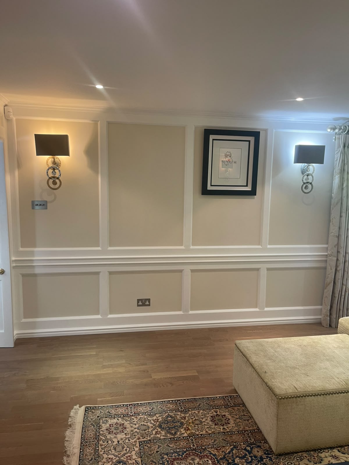 Cream panelled living room wall painted between wall sconces