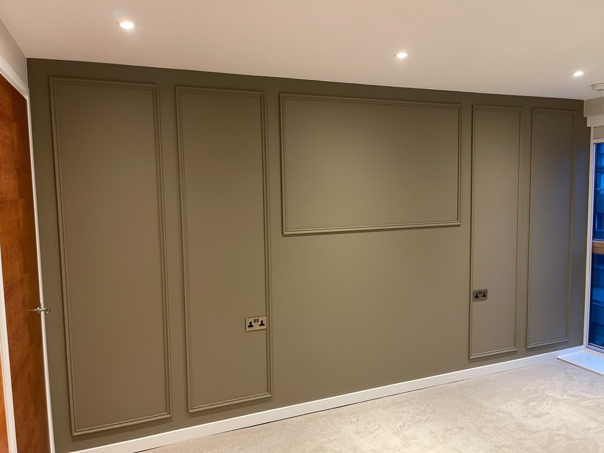 Olive-toned decorative wall in Islington with tall rectangular mouldings and contrasting white skirting and ceiling trim