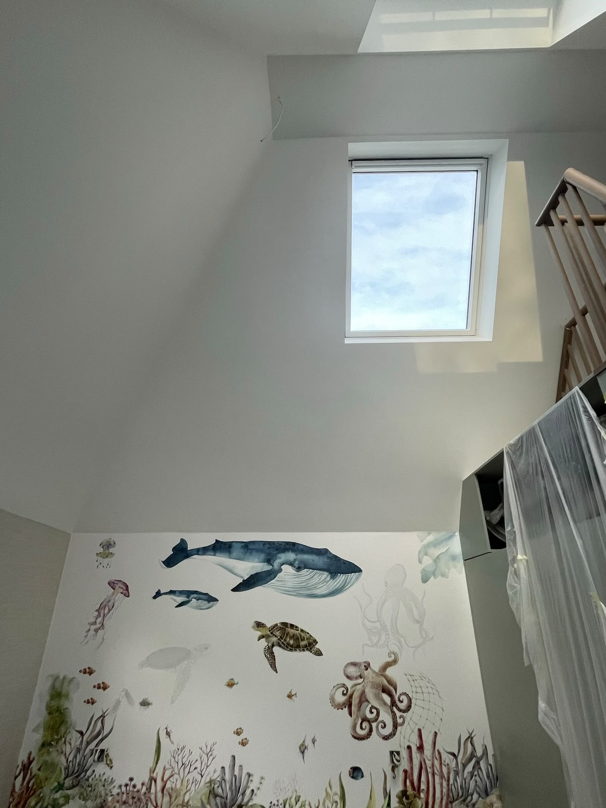 Attic stairwell with freshly painted white walls and a decorative underwater mural feature wall
