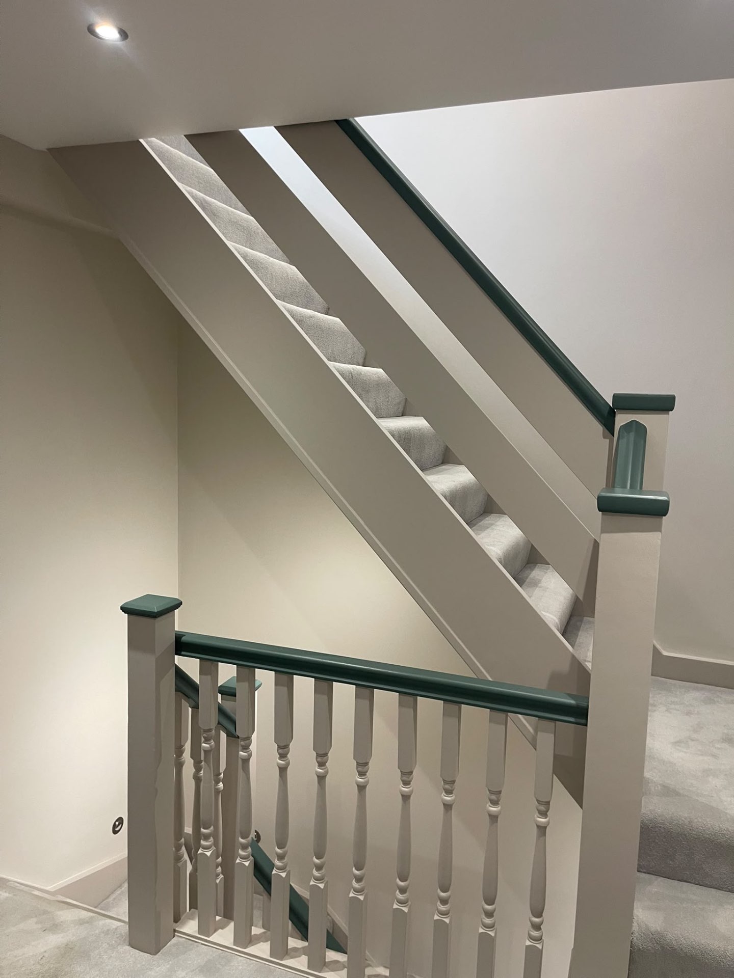 Painted stairwell and landing with finished balustrade and dark green handrail in Hersham
