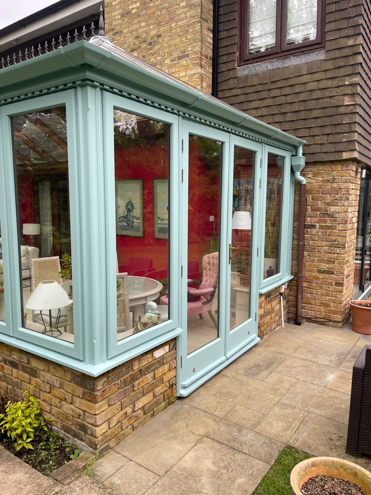 Close-up of a duck-egg painted conservatory with bay window and French doors