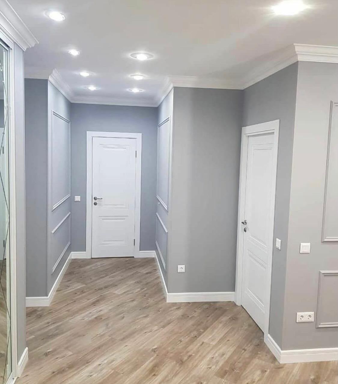 Modern grey hallway with white doors and recessed ceiling lighting