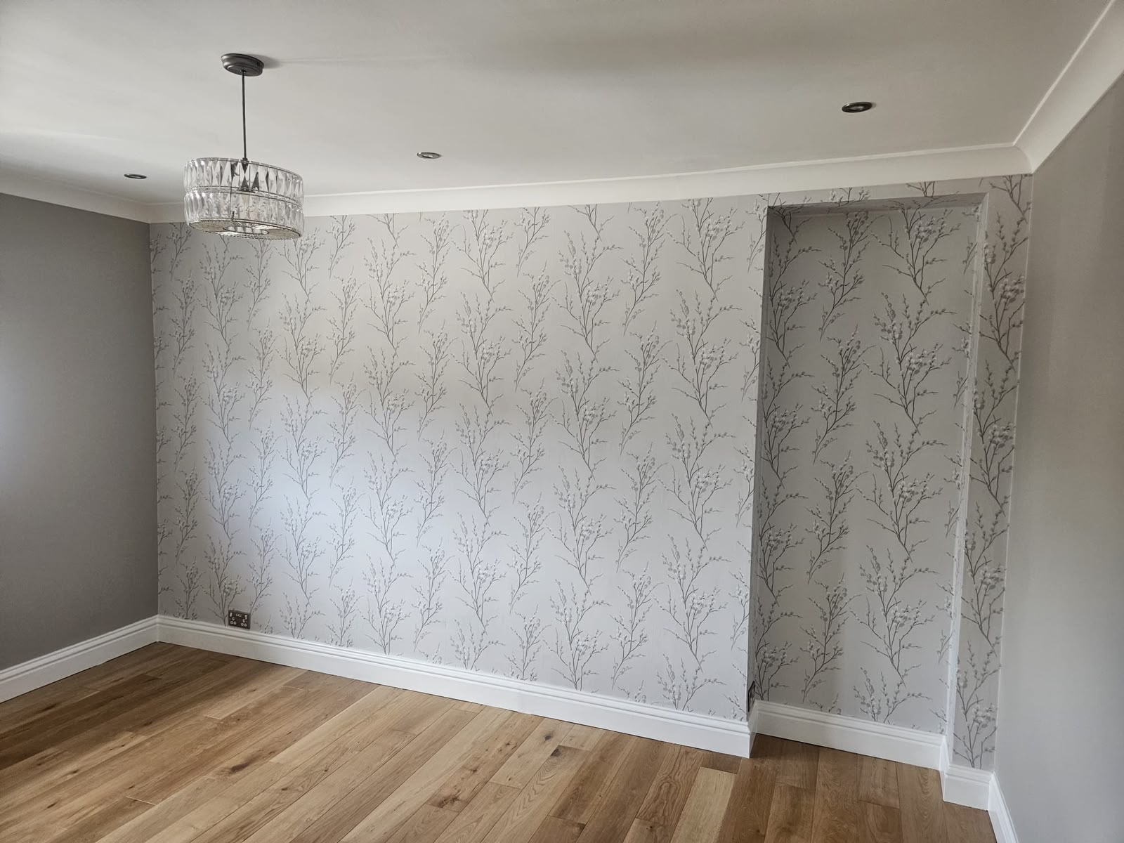 Soft grey willow-branch wallpaper installed across a feature wall and alcove