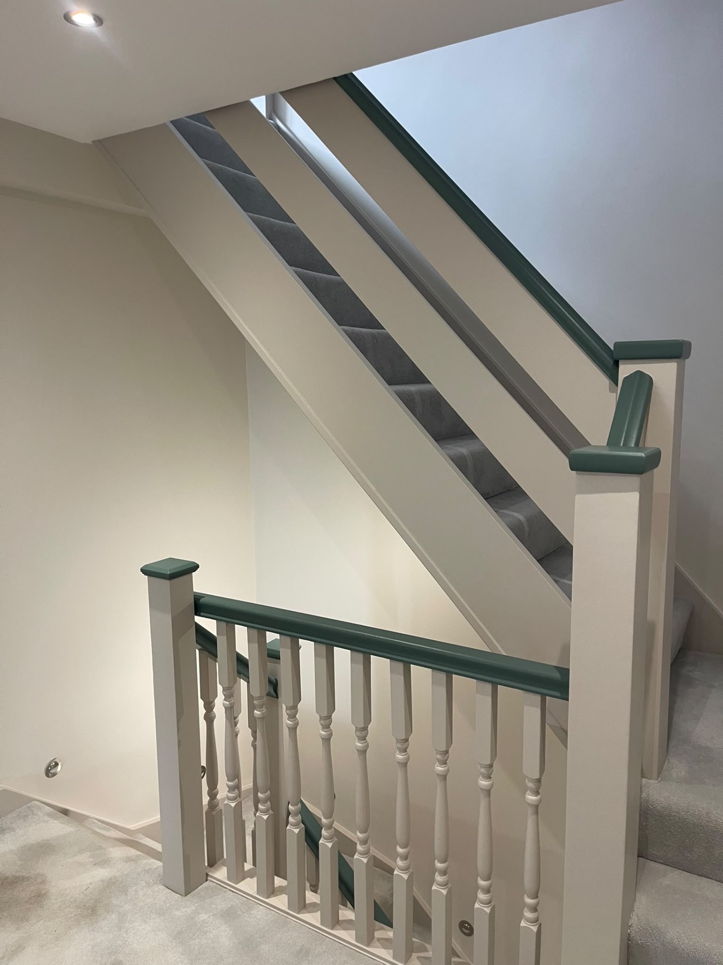 Painted staircase and landing with a contrasting dark green handrail in a Hersham home