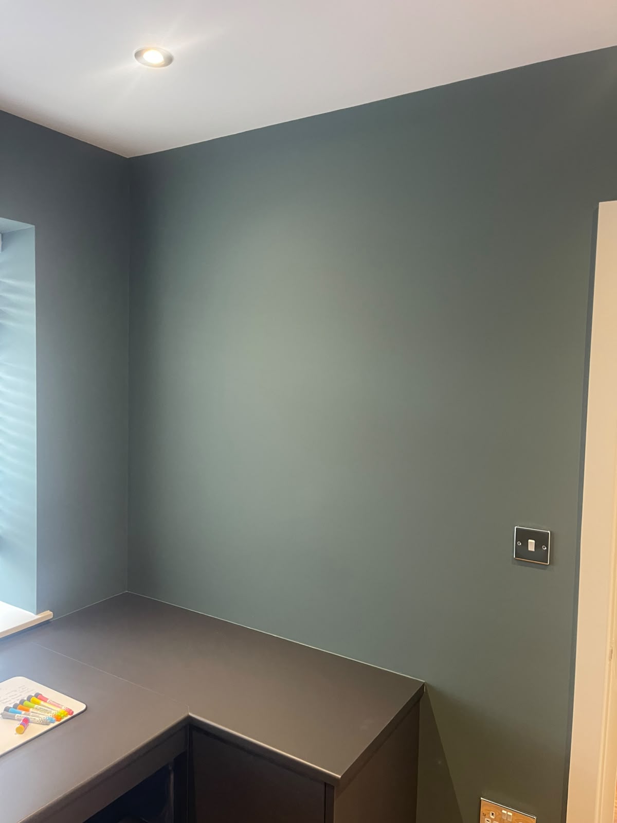 Home office corner painted in deep teal with recessed ceiling lights