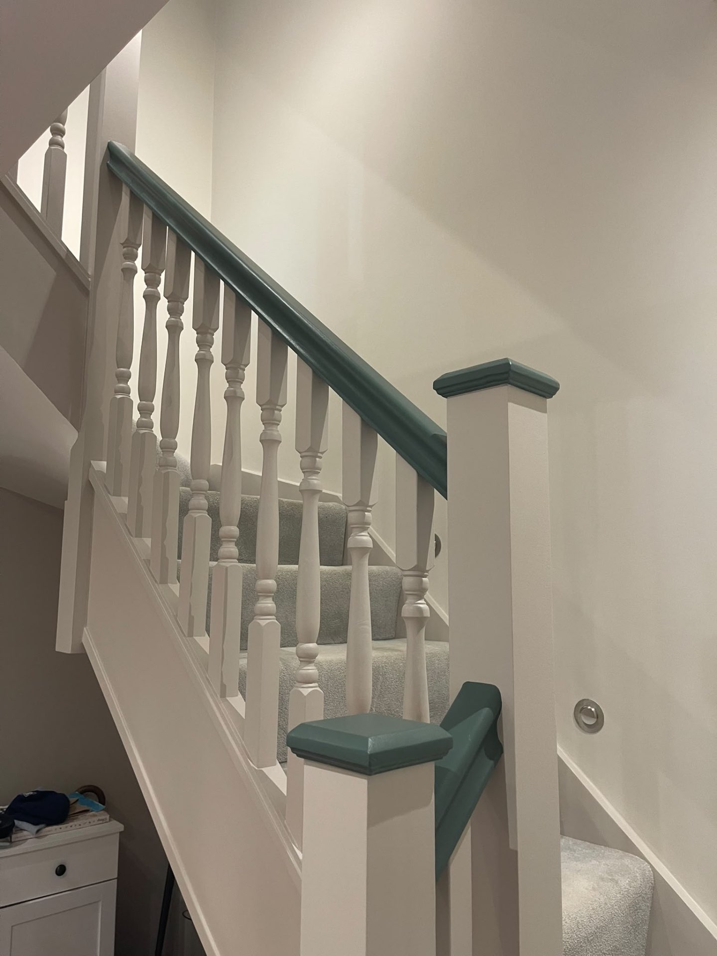 Finished staircase woodwork with light painted spindles and contrasting dark green handrail