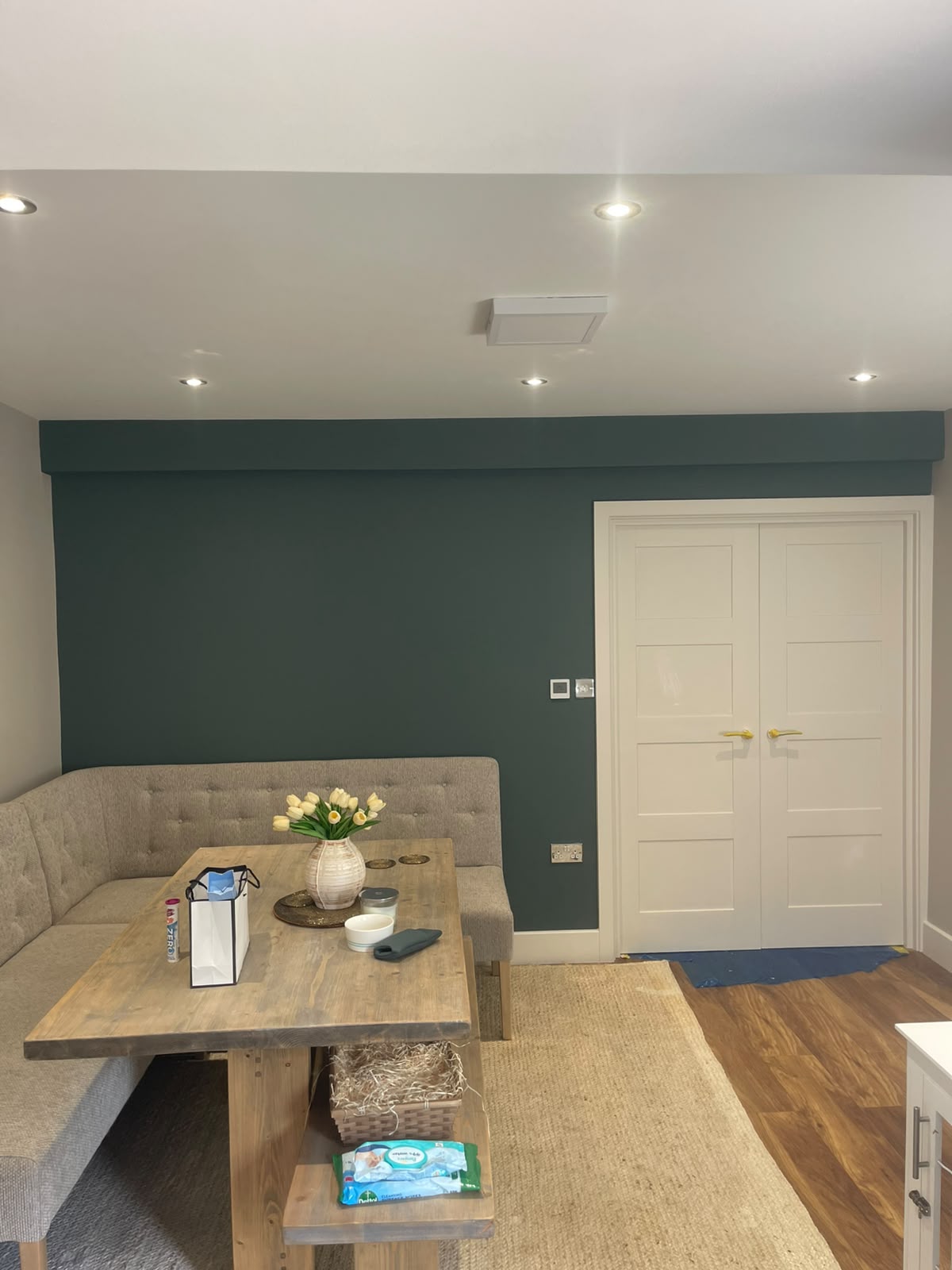 Dining area with a deep teal feature wall and crisp white double doors
