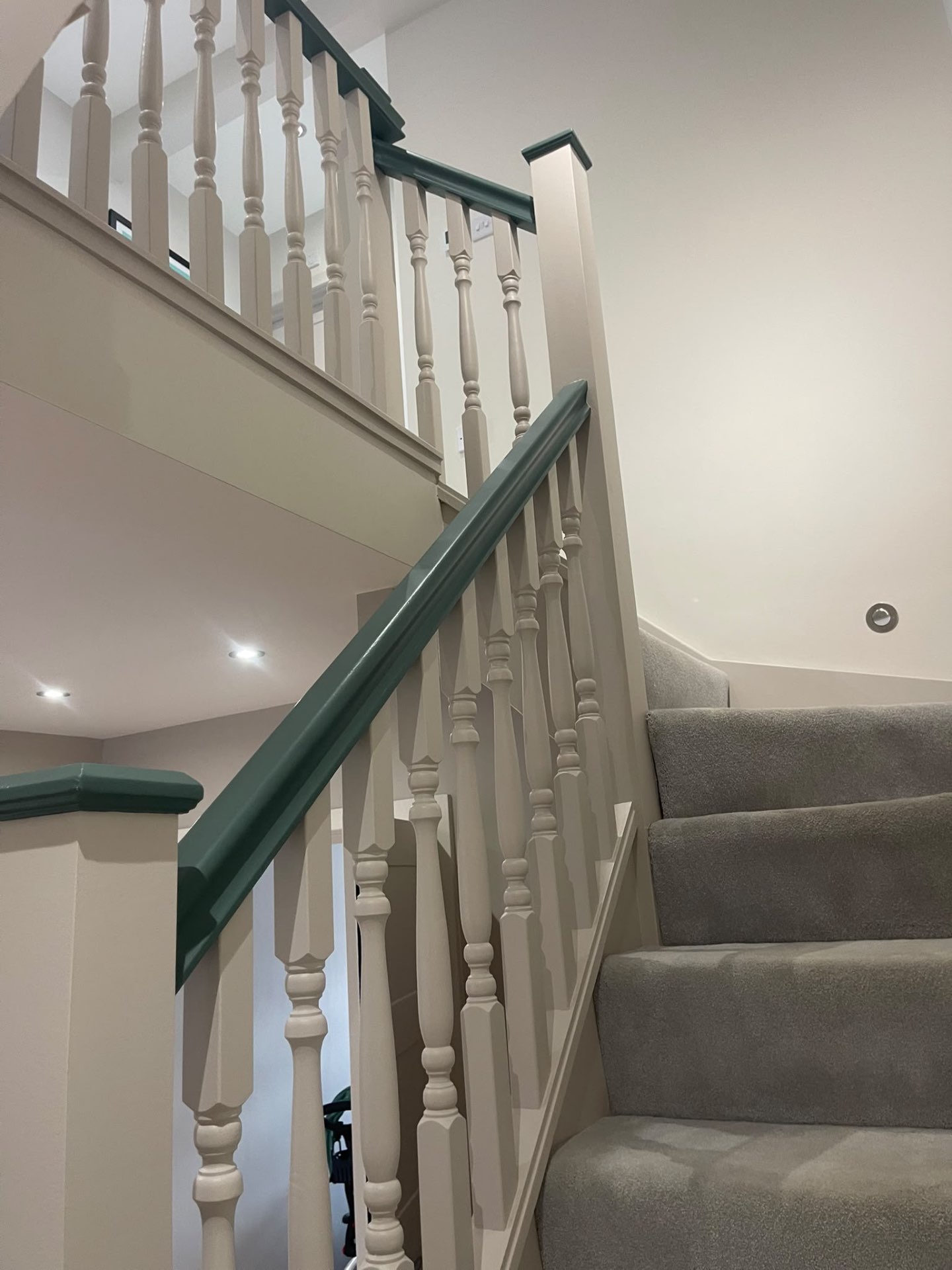 Hersham staircase with painted newel posts, spindles and dark green handrail