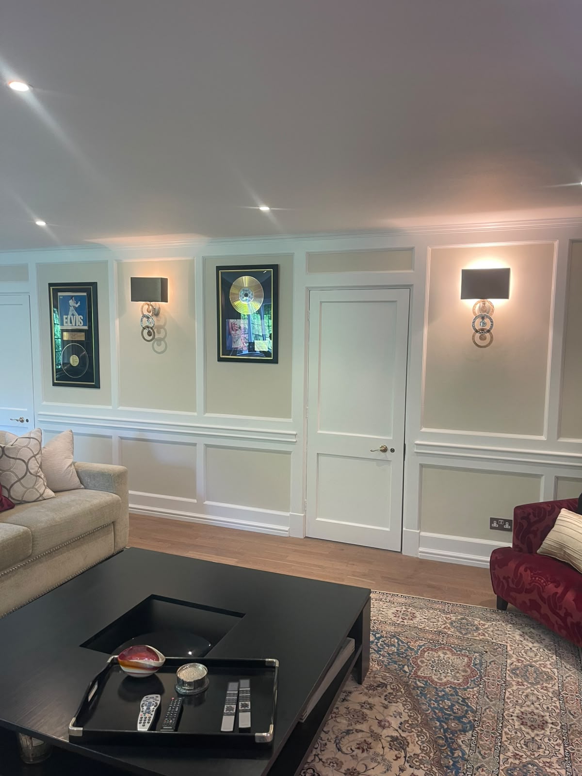 Living room wall featuring tan wainscoting panels and painted trim