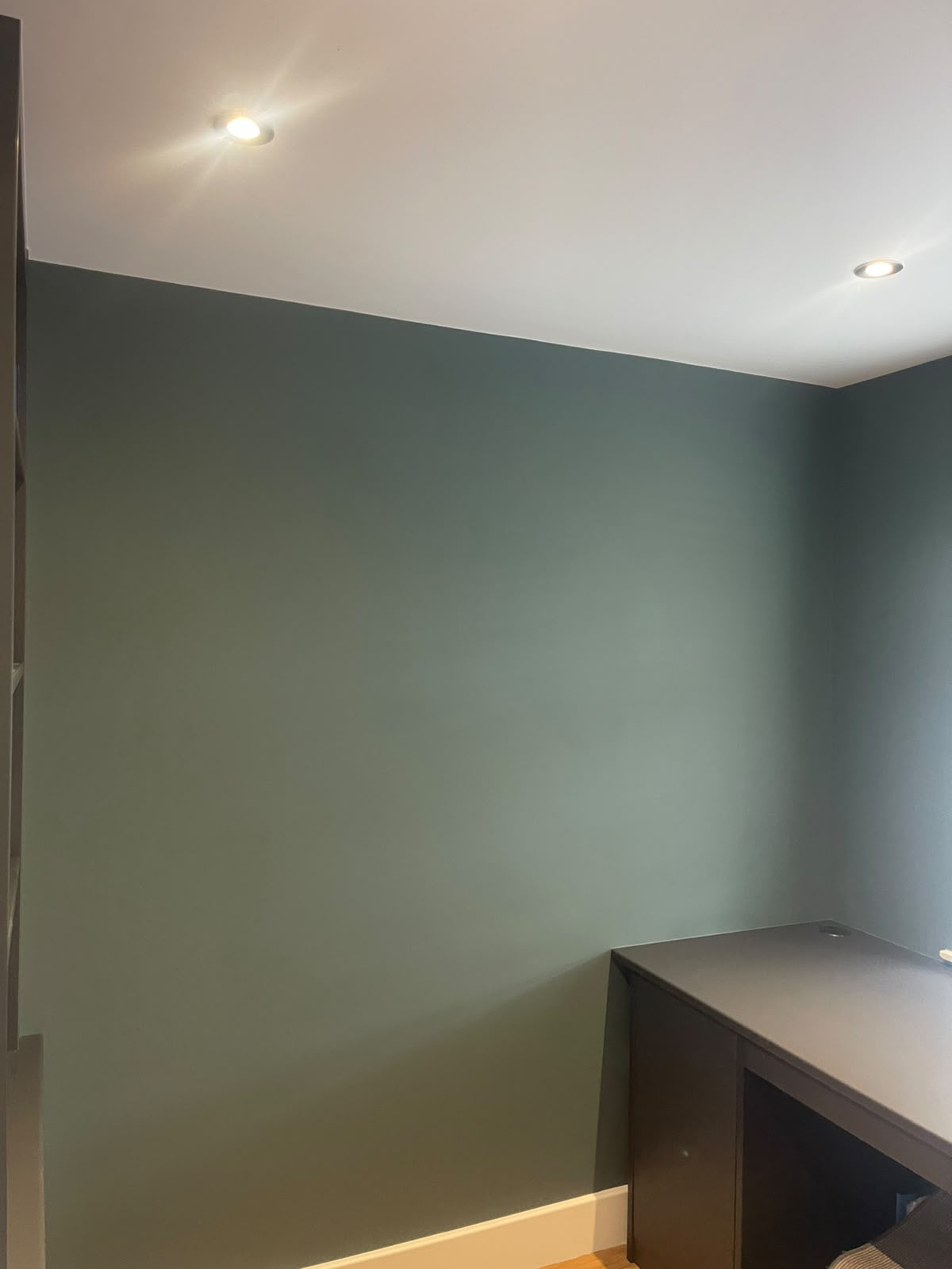 Deep teal painted study wall beneath fresh white ceiling and cornice