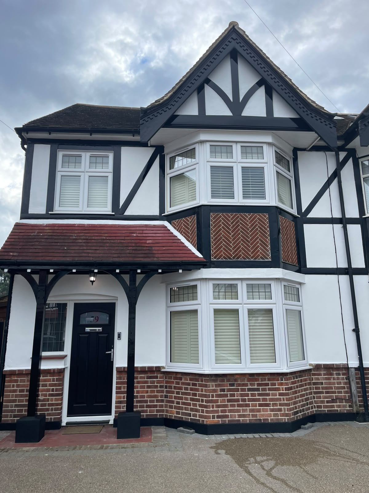 White Tudor-style semi-detached home with freshly painted black timber framing and window trims