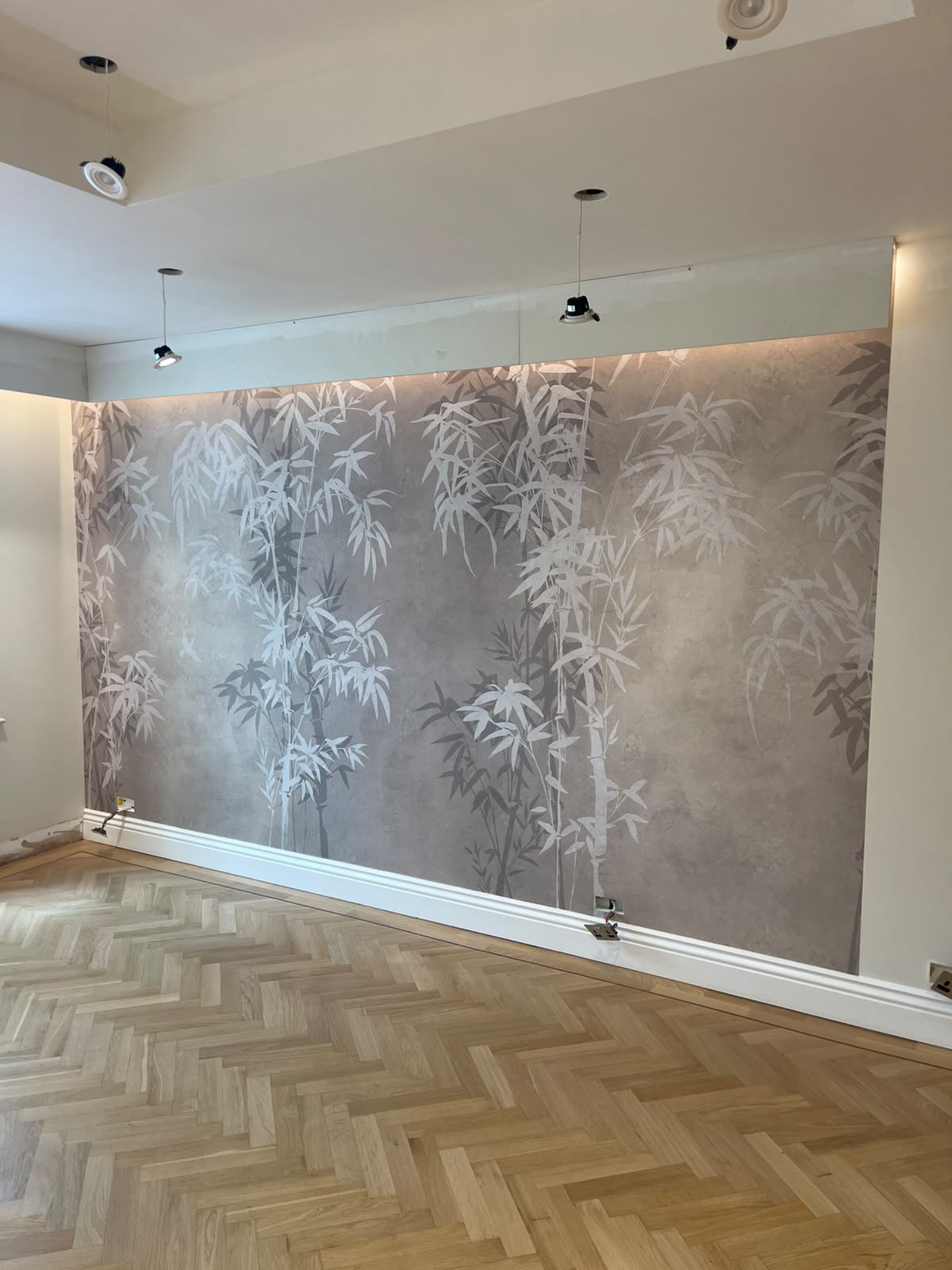 Grey bamboo mural feature wall above herringbone parquet flooring