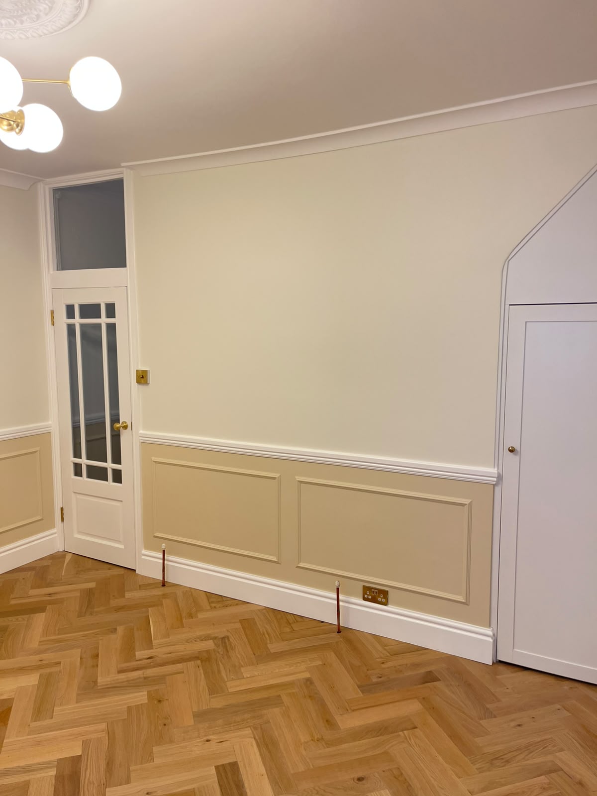 Living room with tan wainscoting, white moulding and painted doors