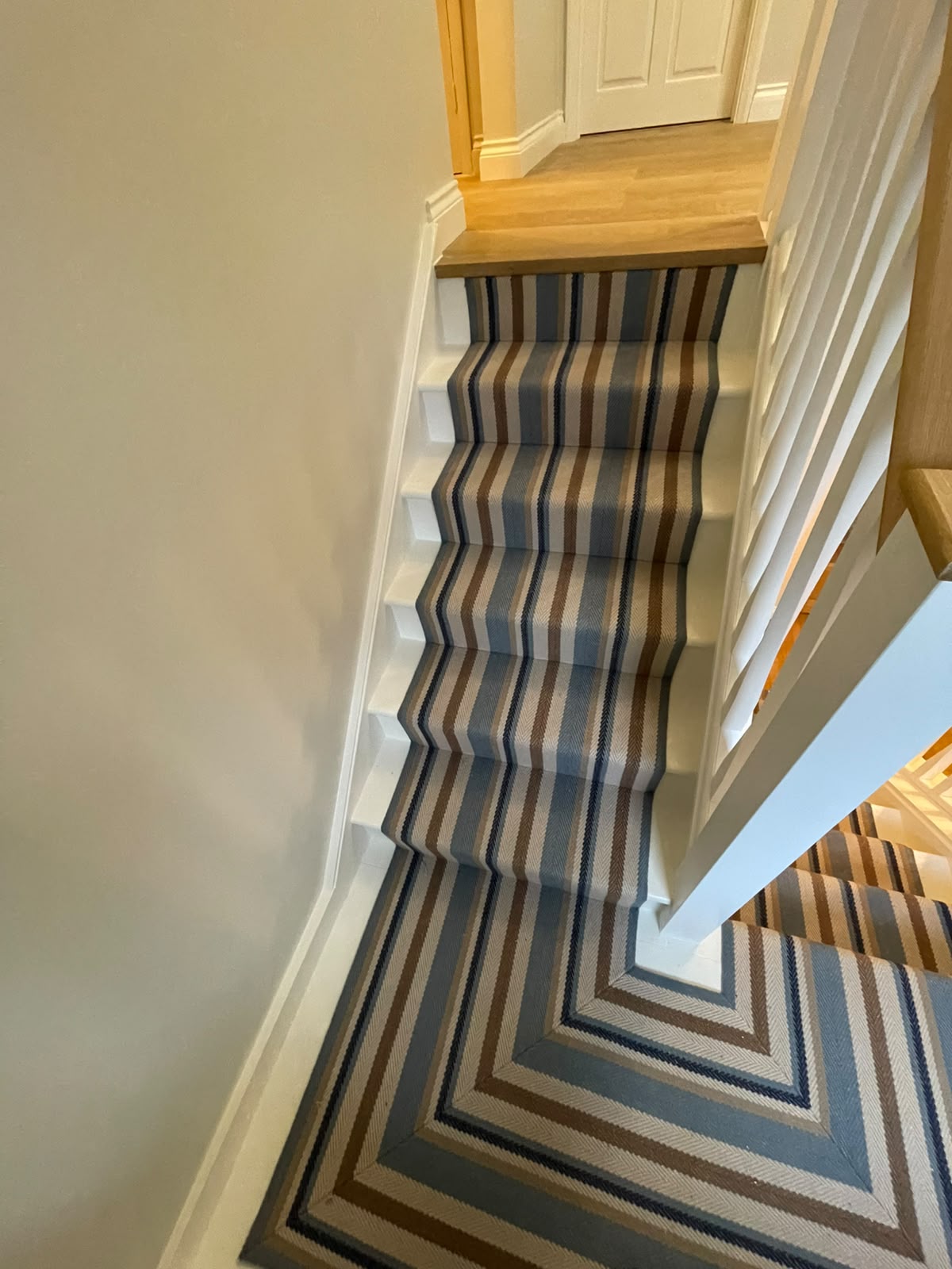 Freshly painted white staircase dressed with a striped runner