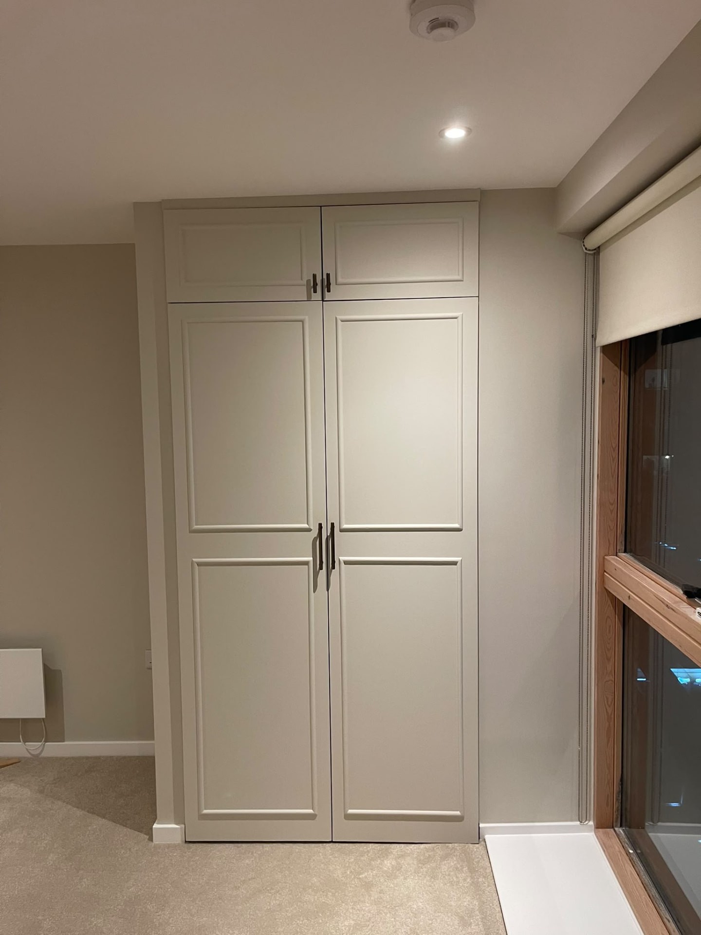 Painted bedroom details in Islington with a panelled cupboard beside a window and coordinated neutral wall finishes