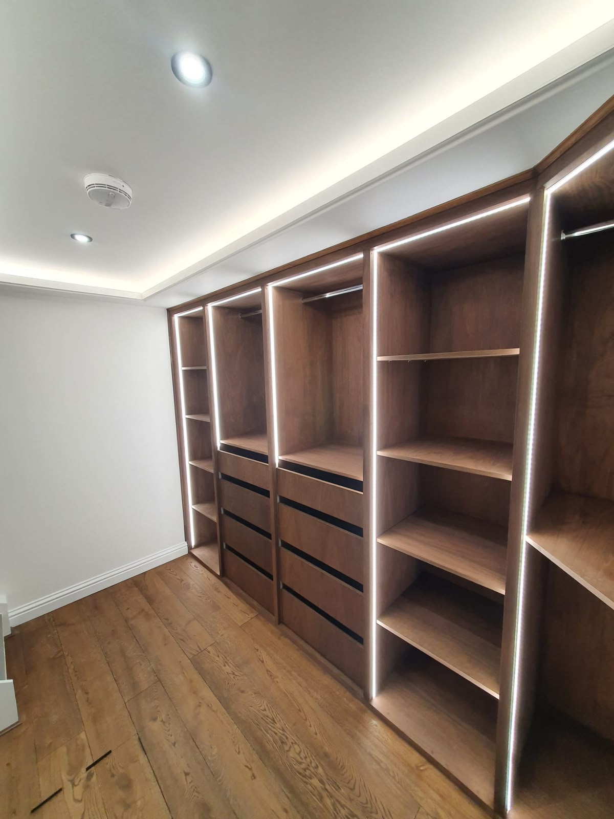 Dark wood walk-in wardrobe with integrated LED-lit vertical dividers