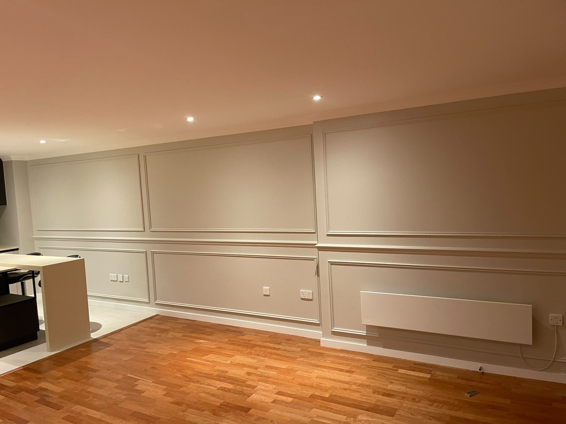 Second view of the Islington living area with painted decorative wall mouldings and exposed wooden floor