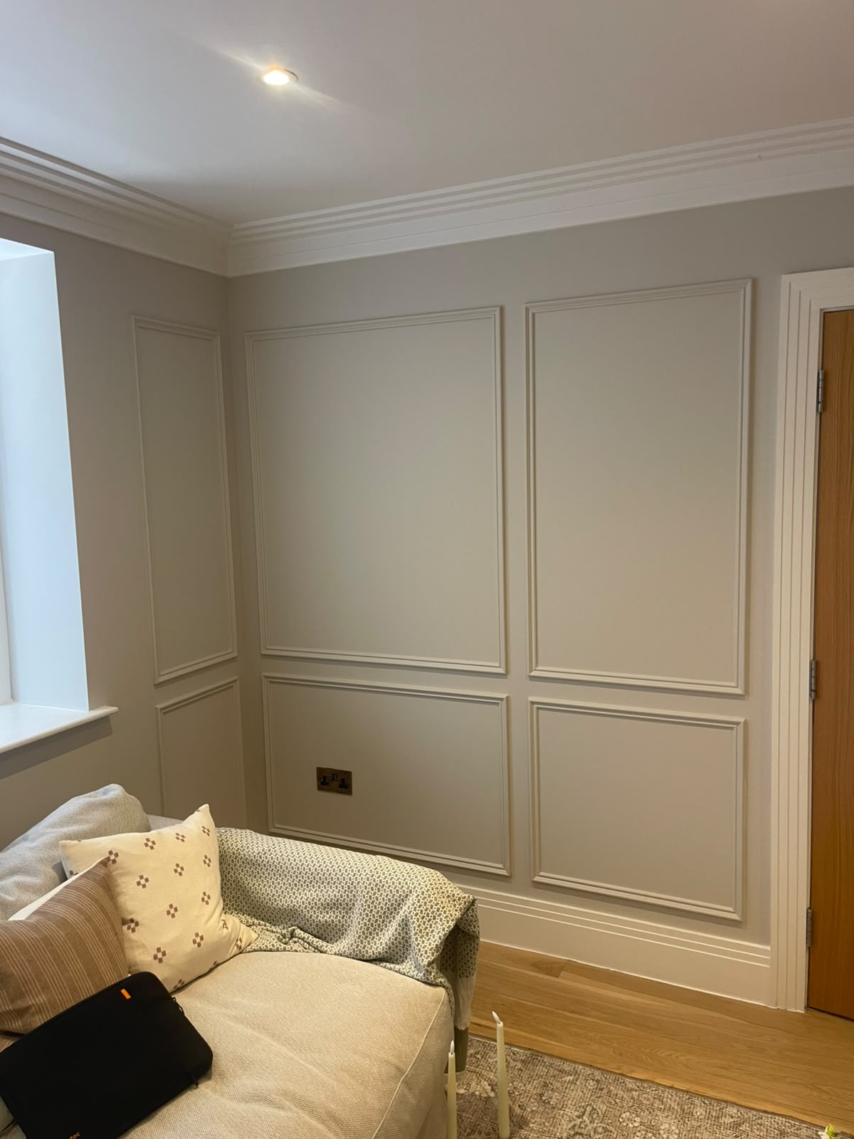 Completed painted wall panelling beside a living room sofa and doorway