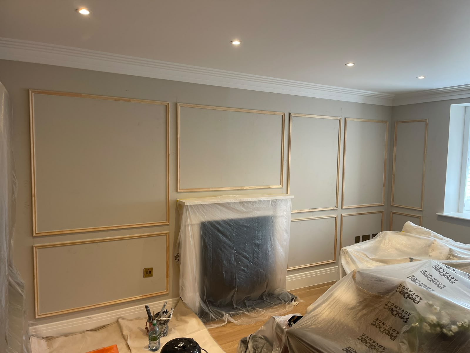 Living room furniture and fireplace covered during wall panelling and decorating work